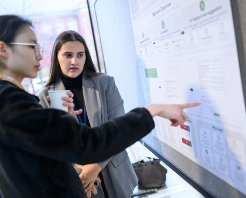 two woman in front of a poster