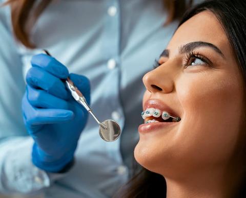 close up of a patient with braces with an examination mirror in front of her mouth