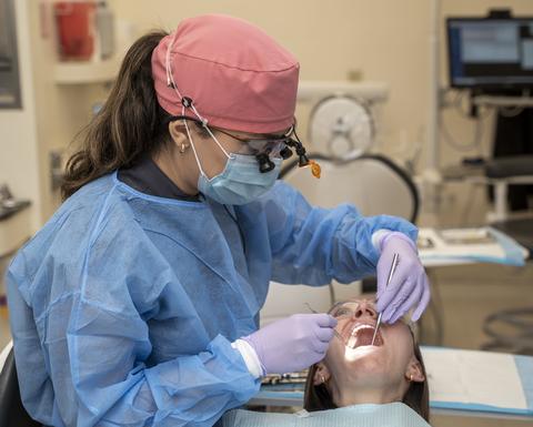 clinician in PPE examining a patients mouth
