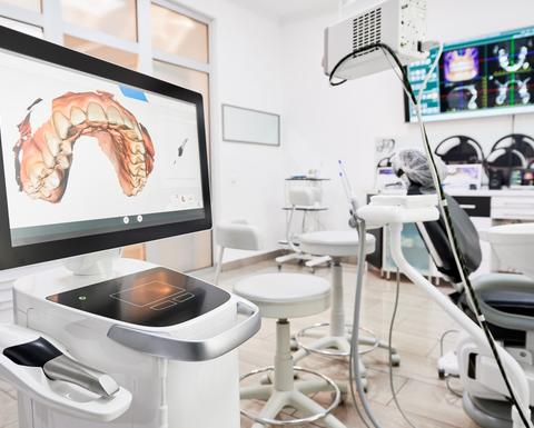 Interior of dental office with modern equipment and dental intraoral scanner with teeth on display, medical system for intraoral scanning.